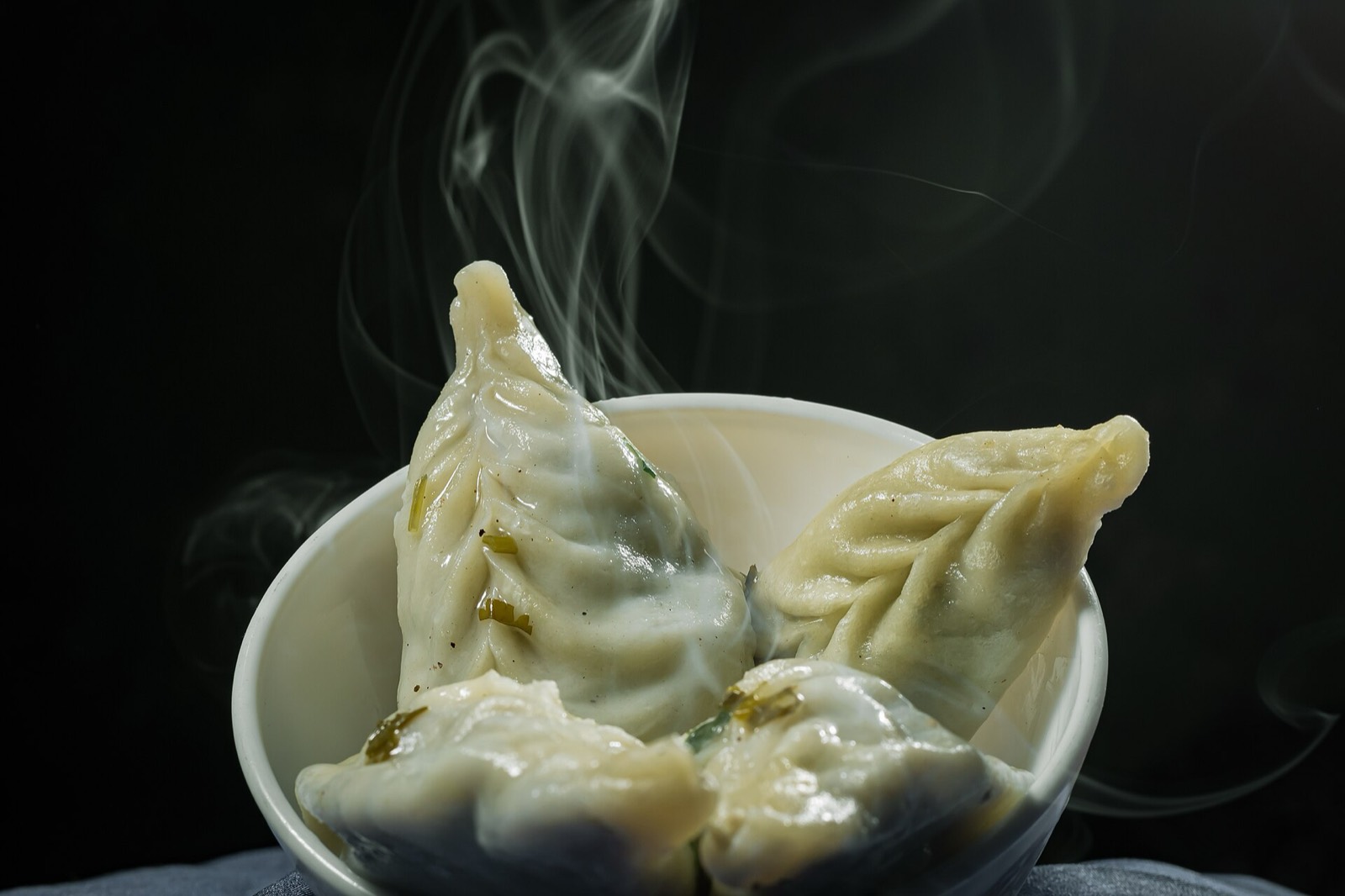A plate of steamed momos showing pleated wrappers
